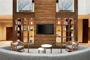 a lobby with two chairs and a tv and bookshelves at Embassy Suites by Hilton Atlanta Alpharetta in Alpharetta