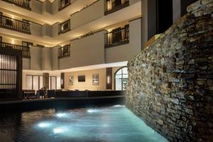 a pool in the middle of a building with a stone wall at Embassy Suites by Hilton Atlanta Alpharetta in Alpharetta