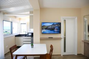 a kitchen with a white table and a tv on the wall at Queen Apartmets Vlore in Vlorë