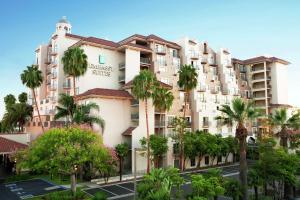 a large apartment building with palm trees in a parking lot at Embassy Suites by Hilton Santa Ana Orange County Airport in Santa Ana