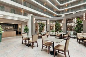 un restaurante con mesas, sillas y plantas en Embassy Suites by Hilton Santa Ana Orange County Airport, en Santa Ana