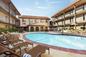 una piscina en un hotel con sillas y un edificio en Embassy Suites by Hilton Lompoc Central Coast en Lompoc