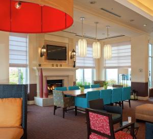 Hilton Garden Inn Allentown Bethlehem Airport في الينتاون: غرفة طعام مع طاولة وكراسي ومدفأة