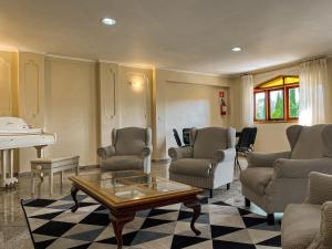 a living room with chairs and a table and a piano at Hotel Nacional Inn Campos do Jordão in Campos do Jordão