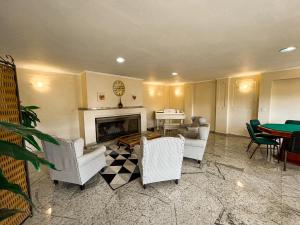 a living room with white chairs and a fireplace at Hotel Nacional Inn Campos do Jordão in Campos do Jordão
