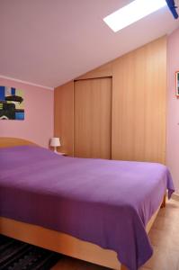 a bedroom with a large bed with purple sheets at Apartments Val in Umag