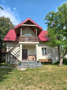 ein Haus mit einem roten Dach und einer Bank in der Unterkunft Agroturystyka Zacisze nad Pilicą in Stromiec