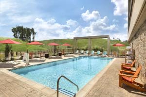 a pool at a hotel with chairs and umbrellas at Home2 Suites by Hilton Grovetown Augusta Area in Augusta