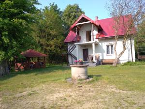 Casa blanca con techo rojo y patio en Agroturystyka Zacisze nad Pilicą, en Stromiec