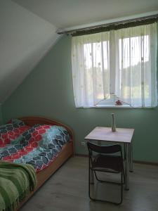 um quarto com uma cama, uma mesa e uma janela em Agroturystyka Zacisze nad Pilicą em Stromiec