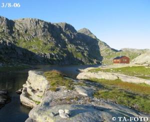 una casa rossa sul lato di un fiume con montagne di Panoramahytte a Norheimsund