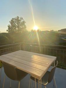 a wooden table and chairs on a balcony with the sun at Harmony Apartment, your holiday home in Rust with balcony & river-view, 5min to Europa-Park in Rust