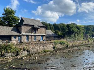 ein altes Steinhaus neben einem Fluss in der Unterkunft Bridgend Barn in Plymouth