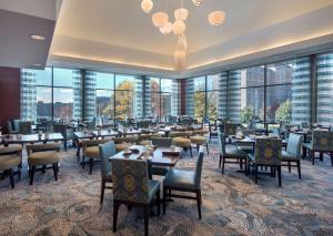 un restaurante con mesas, sillas y ventanas grandes en Hilton Garden Inn Albany Medical Center en Albany