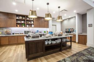 une cuisine avec des placards en bois et un grand îlot dans l'établissement Homewood Suites By Hilton Saratoga Springs, à Saratoga Springs