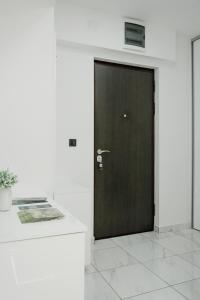 Una puerta marrón en una habitación blanca con una mesa en Luka Apartments Flatiron, en Skopje
