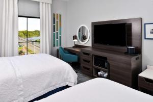 a hotel room with two beds and a flat screen tv at Hampton Inn Cedar Falls Downtown, Ia in Cedar Falls