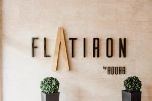 two potted plants in front of a wall with a sign at Luka Apartments - Iconic Flatiron - Free Parking in Skopje