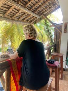 a woman sitting on a bench looking at a tablet at PALM - 2minutes walk to the beach in Nungwi