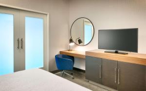 1 dormitorio con escritorio, TV y espejo en Hampton Inn & Suites Anaheim Resort Convention Center, en Anaheim