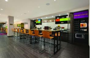 Home2 Suites by Hilton - Oxford في أكسفورد: مطعم مع بار وكراسي برتقال
