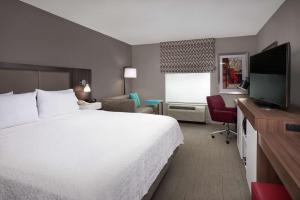 a hotel room with a white bed and a television at Hampton Inn & Suites Oxford-Anniston in Oxford