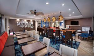 a restaurant with tables and chairs and a bar at Hampton Inn Naples - I-75 in Naples