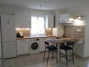una cucina con armadi bianchi, tavolo e lavastoviglie di Appartement T2, 4 personnes, disponible jusqu au Samedi 2 sept 2023 a Le Cannet-des-Maures