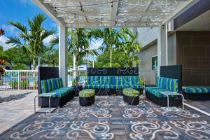 a patio with blue and green chairs and palm trees at Home2 Suites By Hilton Naples I-75 Pine Ridge Road in Naples