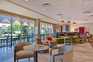 a waiting room with tables and chairs and windows at Home2 Suites By Hilton Naples I-75 Pine Ridge Road in Naples