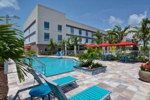a pool at a hotel with chairs and umbrellas at Home2 Suites By Hilton Naples I-75 Pine Ridge Road in Naples