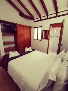 a bedroom with a large white bed with two towels at Hospederia Sandaned in Villa de Leyva