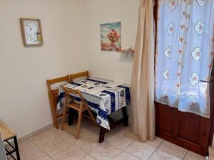 Una habitación con una mesa y sillas con una cortina. en Rustico Porto Pino 30 mt dalla spiaggia, en Porto Pino
