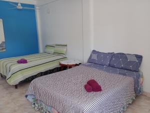 Duas camas num quarto com almofadas roxas em El oso viejo em Puerto Iguazú