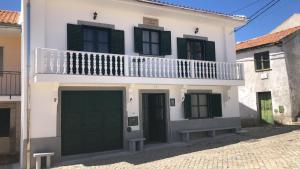 een wit huis met groene deuren en een balkon bij SPA - Casa do Avo BESELGA 
