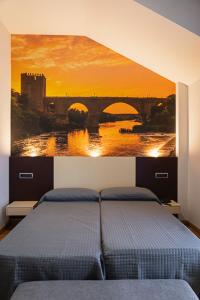 a bedroom with a bed with a painting of a bridge at Hotel-Asador Montes Oretanos in Pulgar