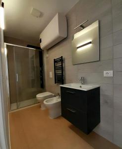 e bagno con servizi igienici, lavandino e doccia. di Piazza Teatro Apartments & Rooms a Trani