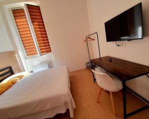 Dormitorio con cama, escritorio y TV en Piazza Teatro Apartments & Rooms, en Trani