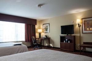 um quarto de hotel com uma cama e uma televisão em Hampton Inn & Suites Watertown em Watertown