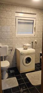ein Badezimmer mit einem WC und einer Waschmaschine in der Unterkunft Apartman stan Konjic in Konjic