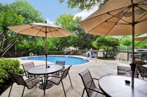 two tables and chairs with umbrellas next to a pool at Hampton Inn Austin North in Austin
