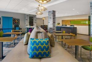 a cafeteria with tables and a bench with pillows at Home2 Suites By Hilton Asheville Airport in Arden