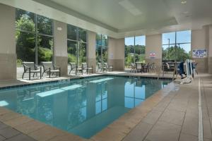 Hampton Inn & Suites-Asheville Biltmore Village, NC في أشفيل: مسبح وكراسي وطاولات في مبنى