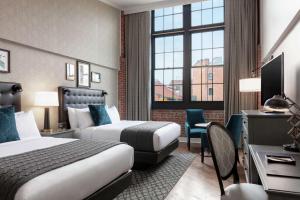 a hotel room with two beds and a desk at Foundry Hotel Asheville, Curio Collection By Hilton in Asheville