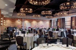 un salón de banquetes con mesas y sillas blancas y lámparas de araña en Foundry Hotel Asheville, Curio Collection By Hilton, en Asheville