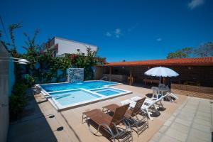 ein Swimmingpool mit Stühlen und einem Sonnenschirm in der Unterkunft Pousada Vovó Zilda Maragogi in Maragogi