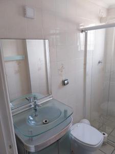 a bathroom with a sink and a toilet and a mirror at Ótimo Apartamento Guilhermina in Praia Grande
