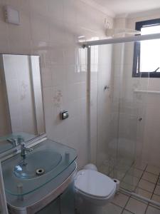 a bathroom with a sink and a toilet and a shower at Ótimo Apartamento Guilhermina in Praia Grande +18 photos