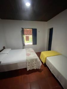 two beds in a small room with a window at Solar dos Pássaros in Pacoti