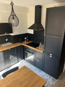 une cuisine avec des armoires noires et une table en bois dans l'établissement Le Perralieres charmant 2 chambres métro Flachet, à Villeurbanne